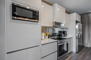 Eine moderne Küche mit Edelstahlgeräten, darunter eine Mikrowelle, ein Ofen und ein Kühlschrank.