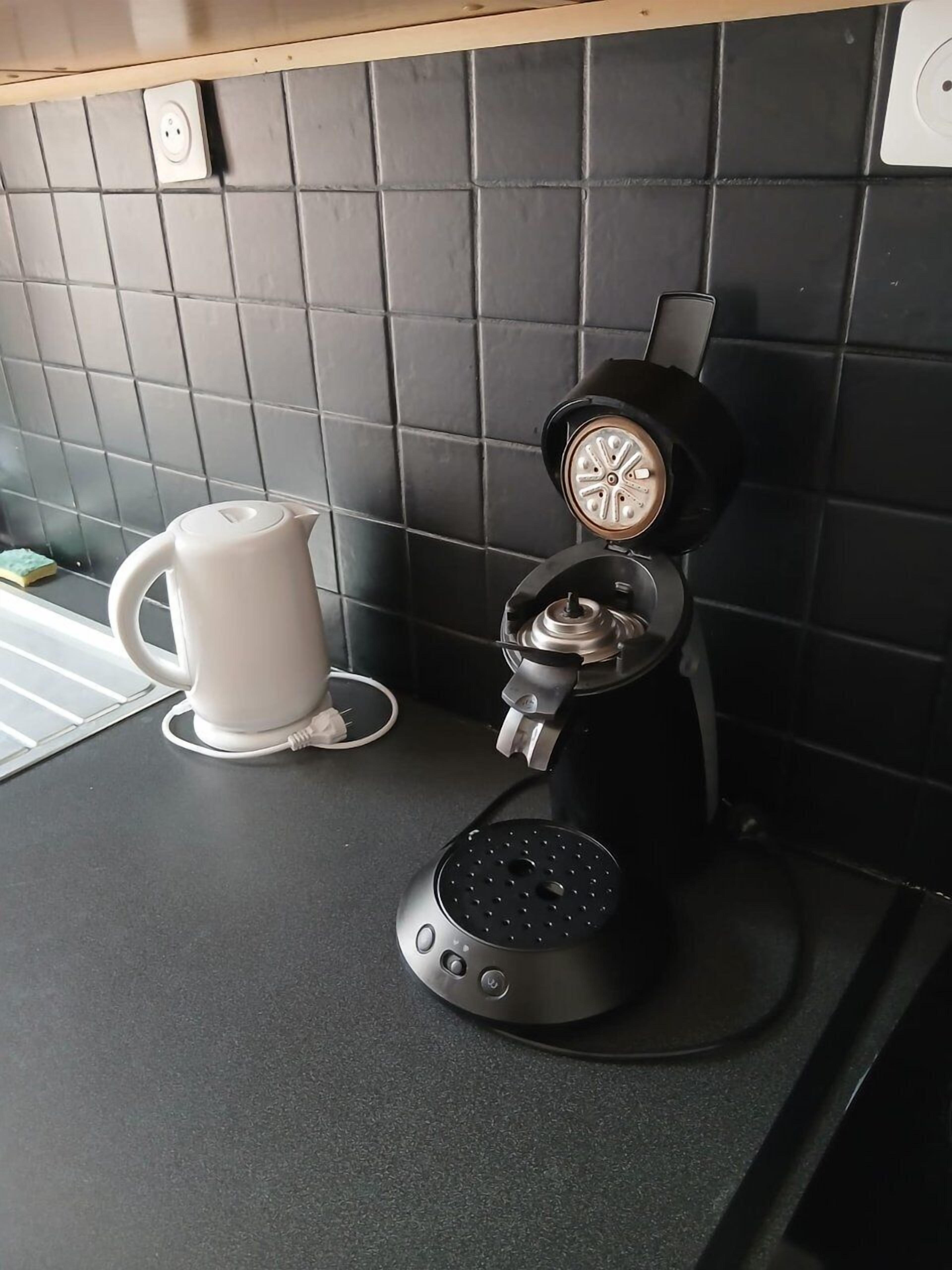 Een koffiezetapparaat op een aanrecht, met een witte mok ernaast.