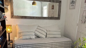 Ett mysigt rum med en säng, ett träbord, en bokhylla, en lampa och en spegel.