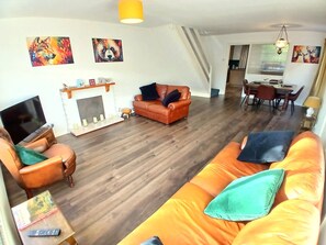 A living room with a fireplace, a sofa, a TV, and a dining area. - House near moors, 10 minutes walk to high street (Guisborough)