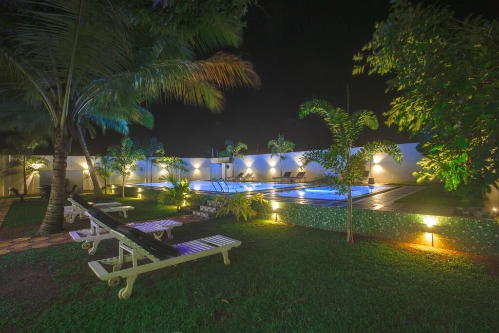 Área de piscina com espreguiçadeiras e palmeiras.