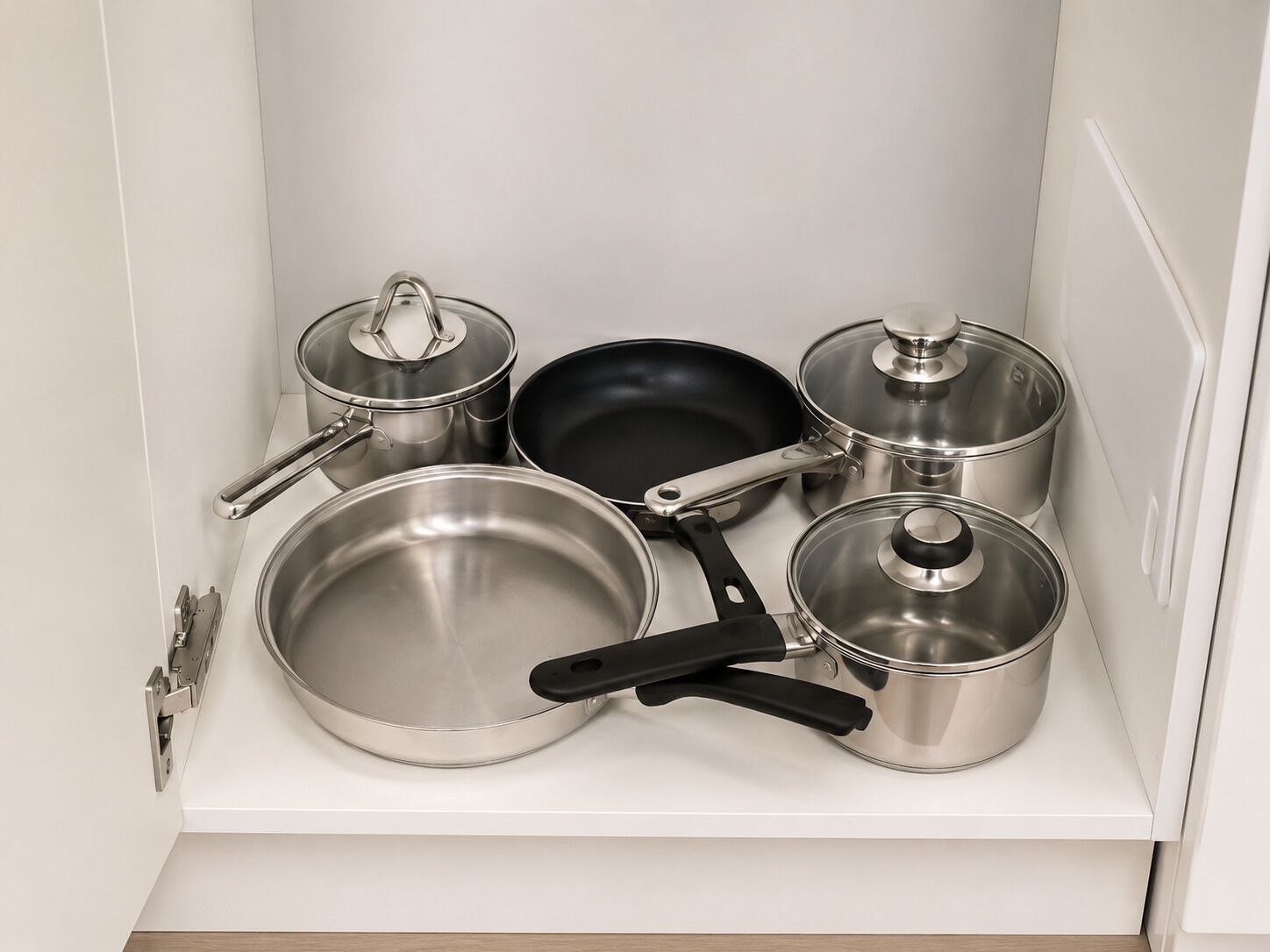 A kitchen with stainless steel cookware, including pots, pans, and a frying pan.