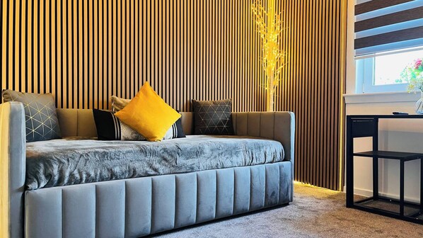A modern bedroom with a sofa bed, a wooden slatted wall, and a small table. - Modern Entire Apartment- Self Checkin Free Parking (Cowdenbeath)