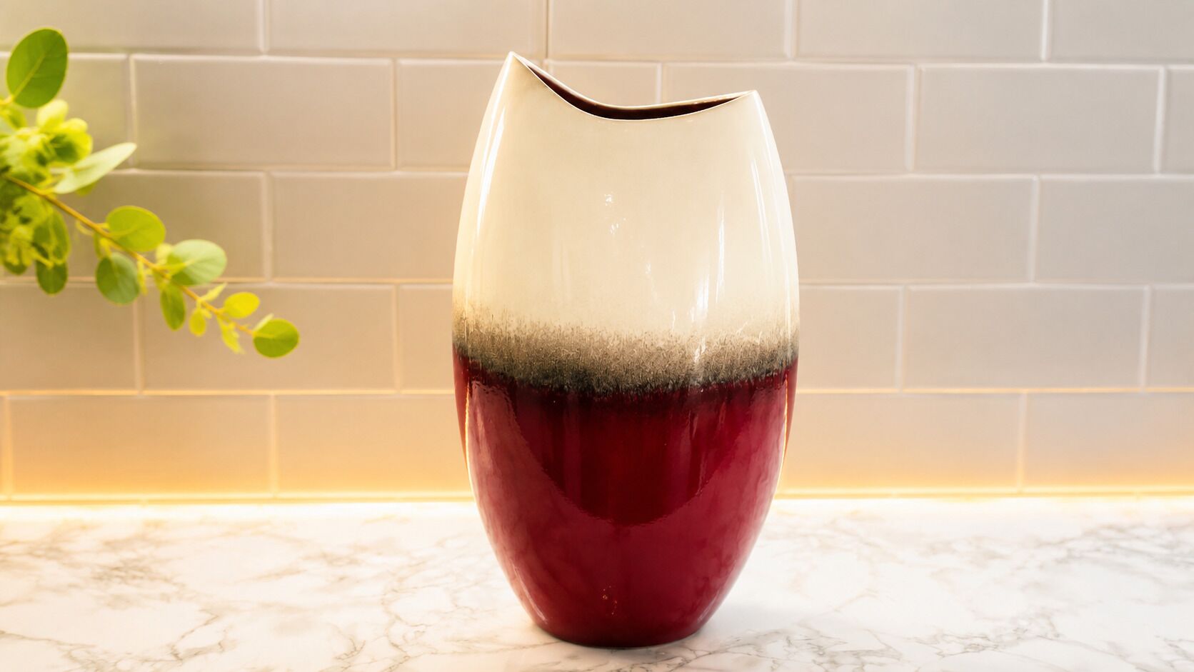 A vase with a gradient color design on a marble countertop.
