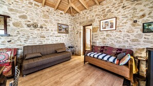 Une pièce rustique avec des murs en pierre, des poutres en bois, un canapé et un banc.