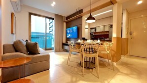 Una sala de estar moderna con un sofá, una mesa de comedor, sillas, un televisor y una zona de cocina.