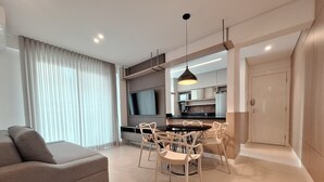 Una sala de estar moderna con un sofá, una mesa de comedor, sillas y un televisor.