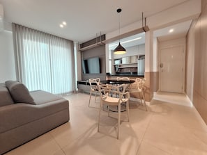 Una sala de estar moderna con un sofá, una mesa de comedor, sillas y un televisor.