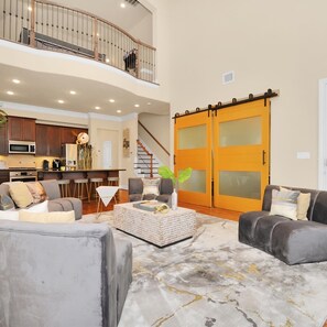 A spacious living area with a high ceiling, a kitchen in the background, and a sliding glass door closet. - Spacious and Lux 2 BR With Game Room & Hot Tub + Gated Community (Houston)