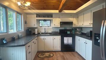 A kitchen with wooden cabinets, a black stove, and a refrigerator.