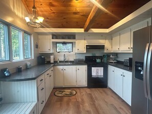 A kitchen with wooden cabinets, a black stove, and a refrigerator. - Merry Grinchmas! Theme getaway, limited availability!! Free photo ops! (Embden)
