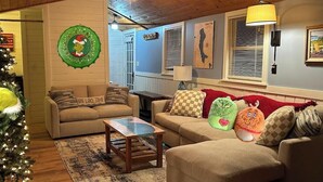 A cozy living room with two sofas, a coffee table, a Christmas tree, and wall decorations. - Merry Grinchmas! Theme getaway, limited availability!! Free photo ops! (Embden)