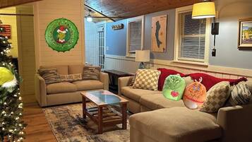 Een gezellige woonkamer met twee banken, een salontafel, een kerstboom en decoratieve wandversiering.