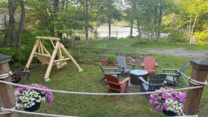 A backyard with a swing set, Adirondack chairs, a small table, and flower pots. - Merry Grinchmas! Theme getaway, limited availability!! Free photo ops! (Embden)