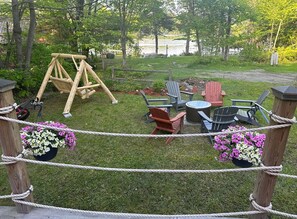 A backyard with a swing set, Adirondack chairs, a small table, and flower pots. - Merry Grinchmas! Theme getaway, limited availability!! Free photo ops! (Embden)