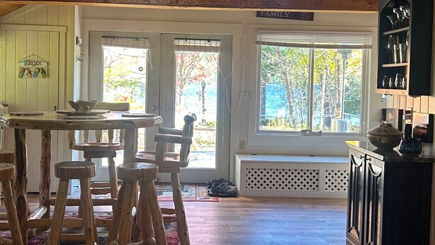 A spacious kitchen with wooden beams, a dining area with stools, and a view of the outdoors through large windows. - Merry Grinchmas! Theme getaway, limited availability!! Free photo ops! (Embden)