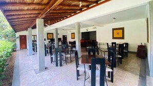 Un comedor de concepto abierto con varias mesas y sillas, piso de baldosas y techo de madera.