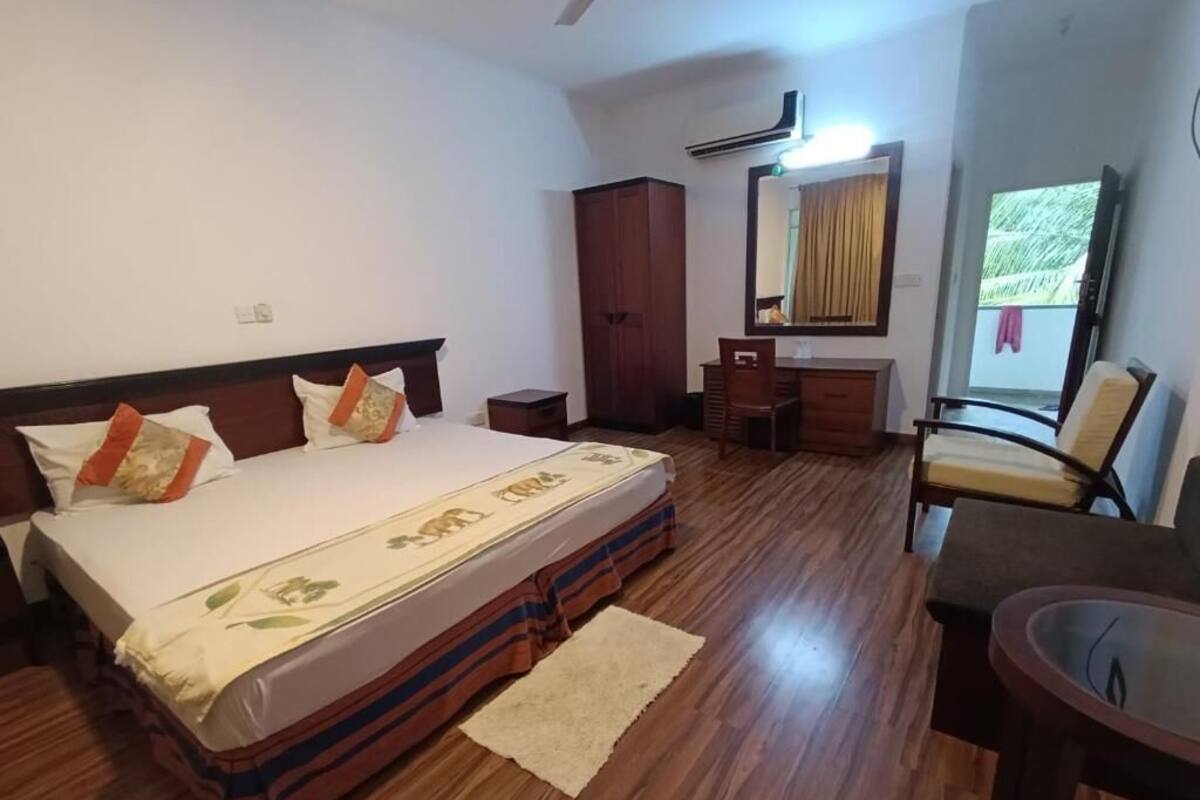 A bedroom with a bed, a desk, a chair, a wardrobe, and a mirror.