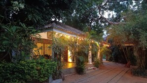 Un edificio con techo de tejas, rodeado de vegetación y un sendero de grava.