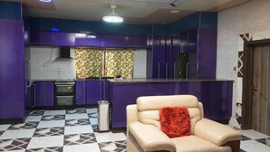 A modern kitchen with purple cabinets, a central island, and a patterned floor. - Zion Apartment  (Old-Yundum)