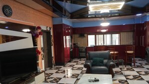 A living room with a TV, a sofa, a coffee table, and a dining area with chairs. - Zion Apartment  (Old-Yundum)