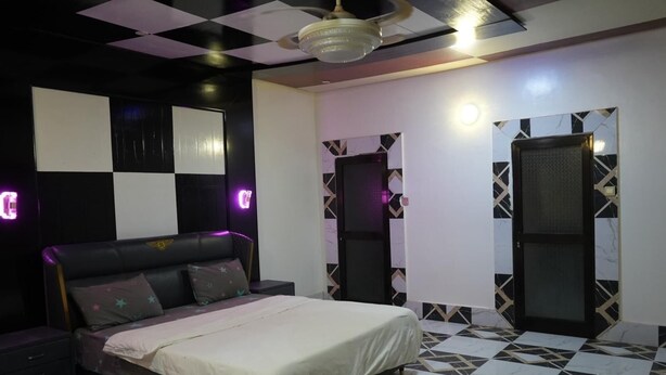 A bedroom with a bed, a ceiling fan, and a wall with a geometric pattern. - Zion Apartment  (Old-Yundum)