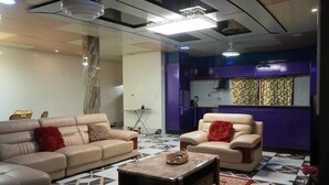 A living room with two sofas, a coffee table, and a kitchen area with purple cabinets. - Zion Apartment  (Old-Yundum)