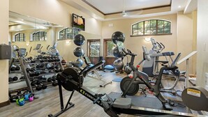 Un gimnasio en casa con equipo de ejercicio, un televisor y un espejo grande.