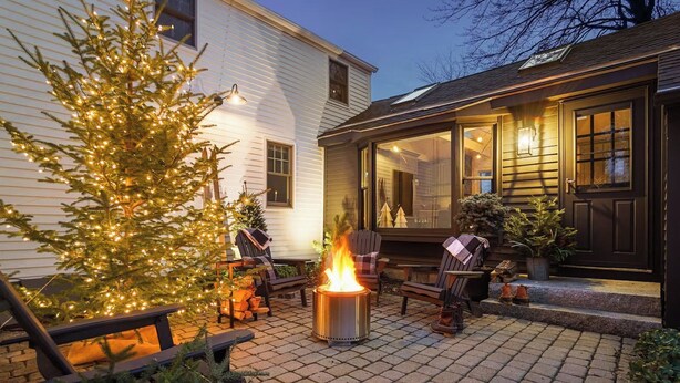A patio with a fire pit, outdoor seating, and a Christmas tree. - The School Street House • Dock Square Village (Kennebunkport)