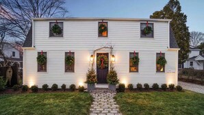 A two-story house with a front porch, a Christmas tree, and wreaths on the windows. - The School Street House • Dock Square Village (Kennebunkport)