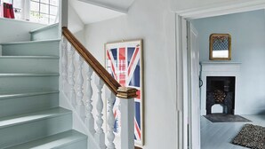 A staircase with white balusters and a wooden handrail, leading to a room with a fireplace and a framed picture on the wall. - No 2 Precentors Court (York)