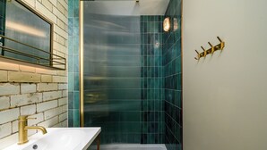 A bathroom with a white sink, gold faucet, and a towel rack on the wall. - Brixton Lofts - Deluxe Studio (No.2) (London)