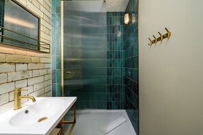 A bathroom with a white sink, gold faucet, and a towel rack on the wall. - Brixton Lofts - Deluxe Studio (No.2) (London)