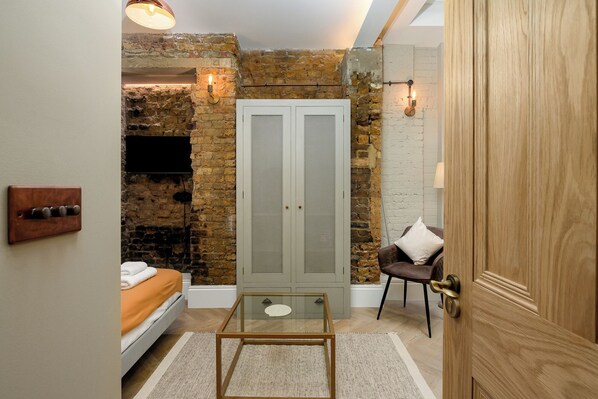 A room with a bed, a glass table, a wardrobe, and a door. - Brixton Lofts - Deluxe Studio (No.2) (London)