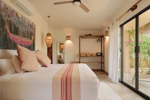 Un dormitorio con cama, ventilador de techo, ventana grande y vista al exterior.