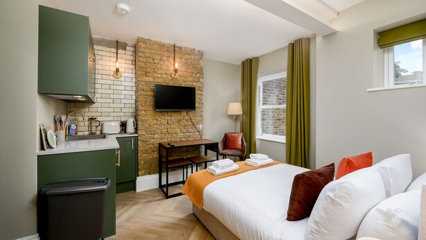 Une chambre d’hôtel équipée d’un lit, d’un bureau, d’une télévision et d’une kitchenette.