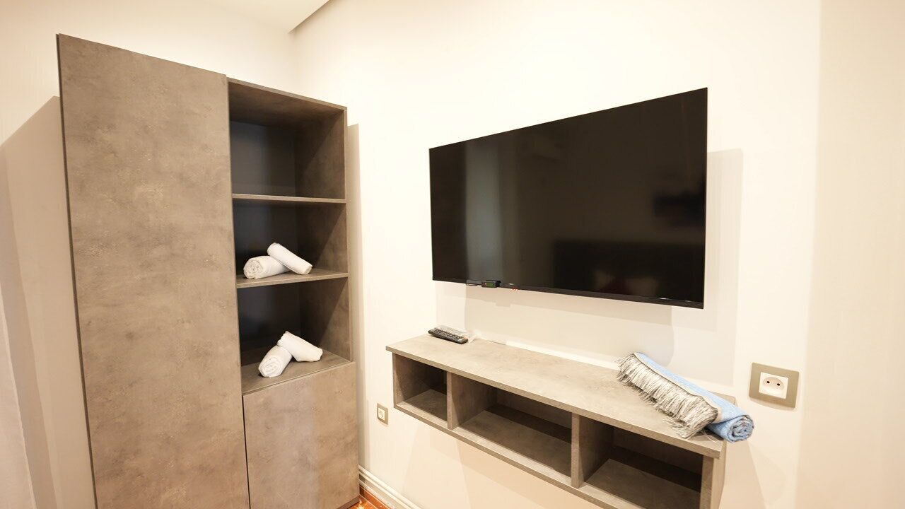 A room with a large wardrobe, a mounted flat-screen TV, and a built-in shelf unit.
