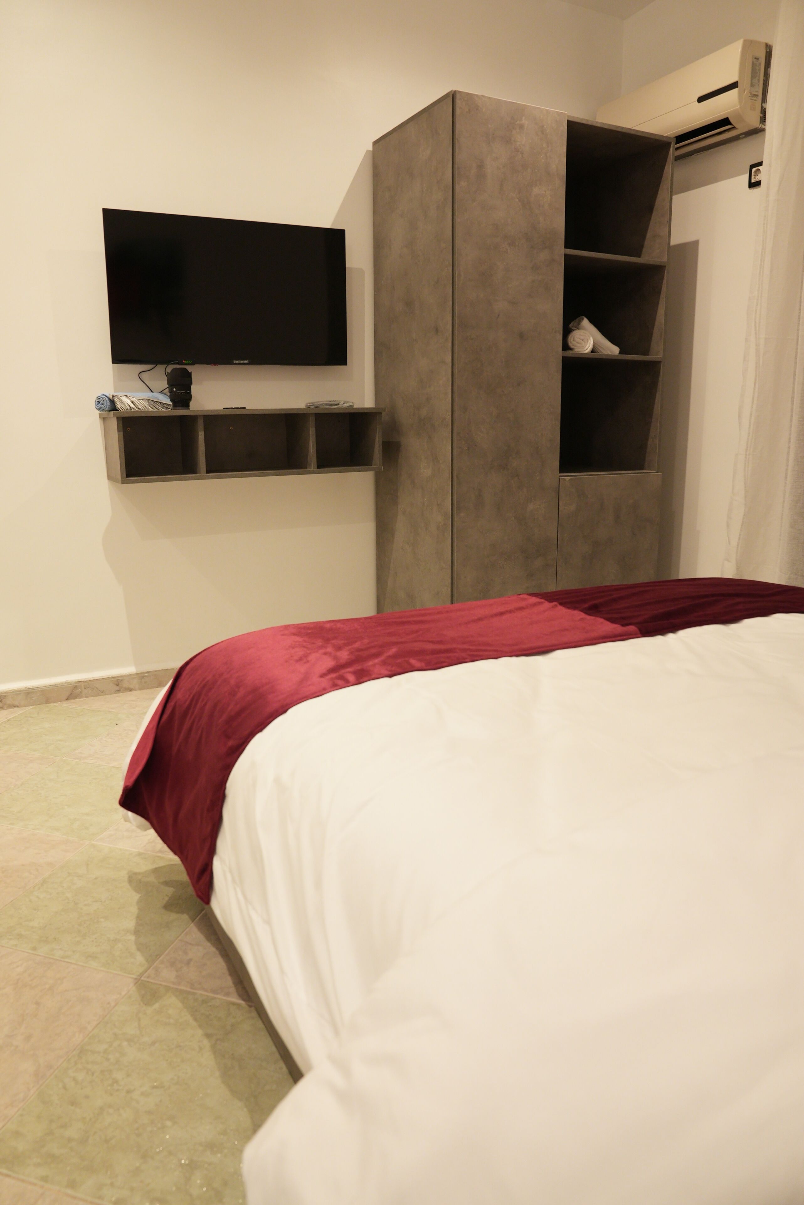 A bedroom with a bed, a TV mounted on the wall, and a wardrobe.