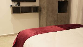 A bedroom with a bed, a TV mounted on the wall, and a wardrobe.