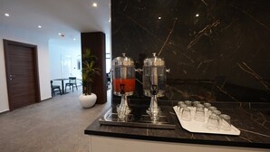 Un moderno vestíbulo de hotel con una recepción de mármol, un área de descanso y una planta grande en maceta.