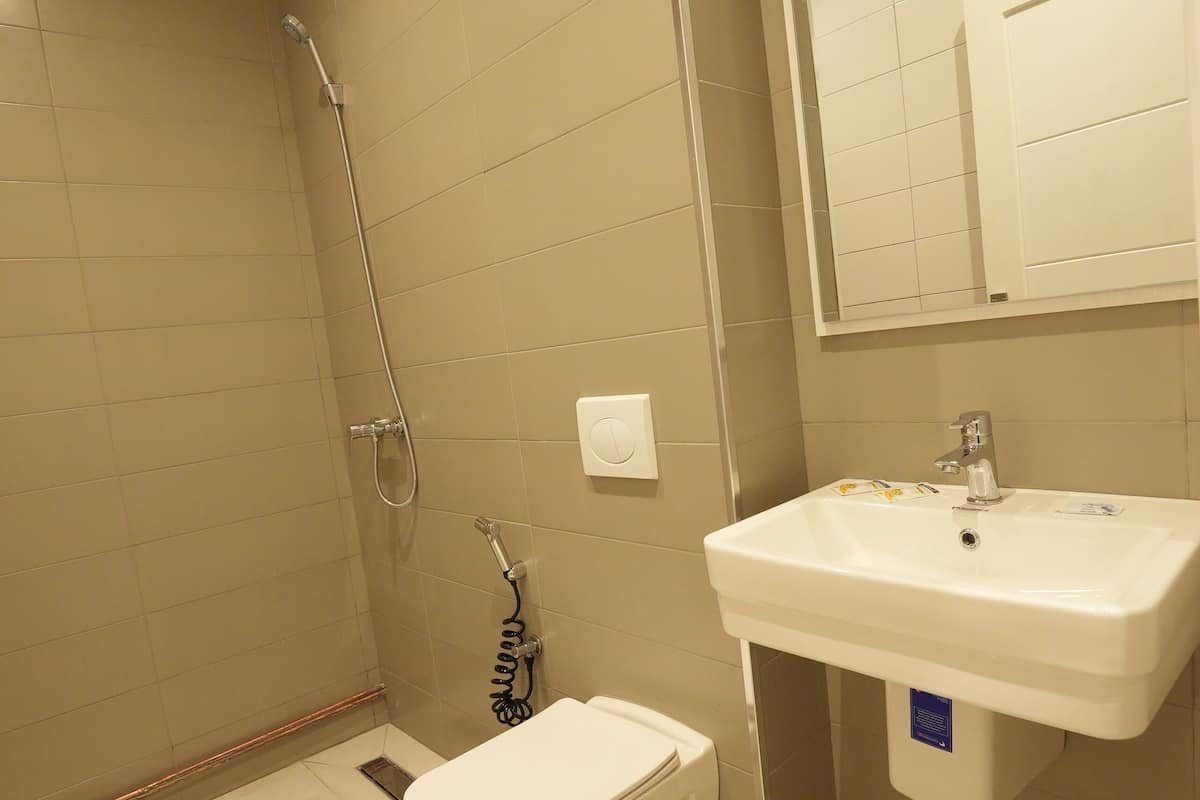 A bathroom with a shower, toilet, sink, and mirror.