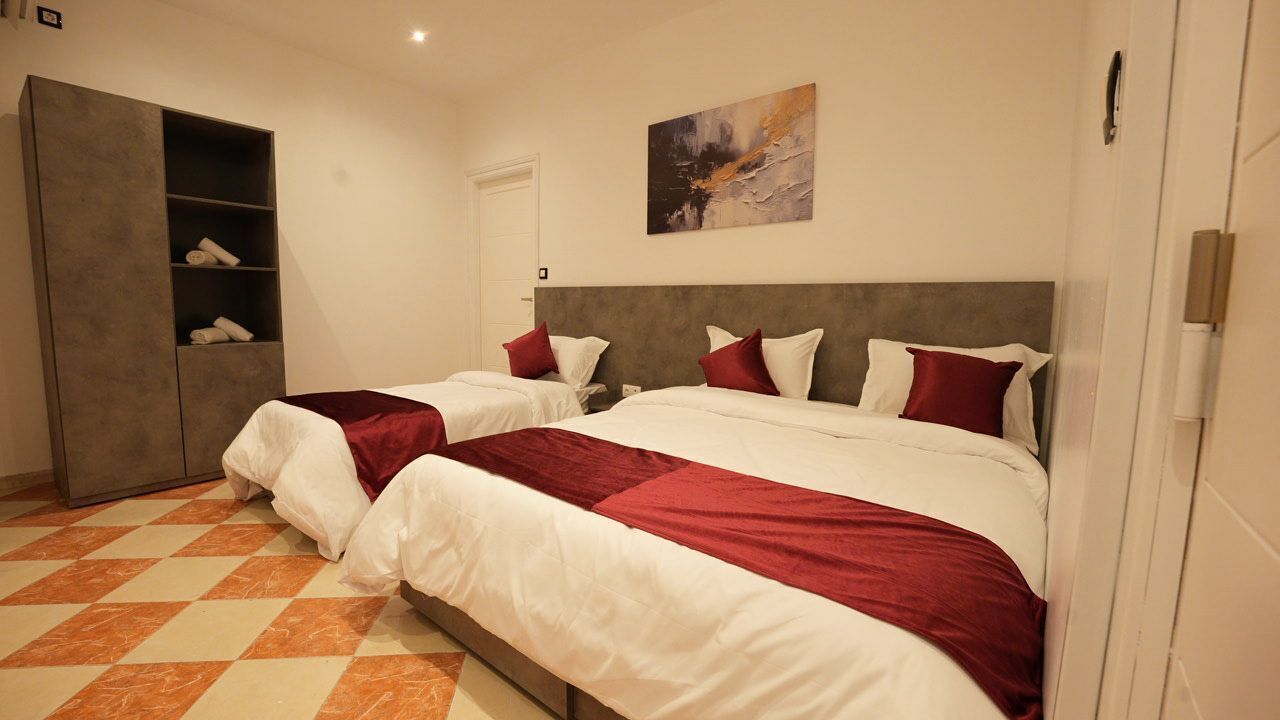 Habitación de hotel con dos camas, un armario, un cuadro en la pared y una recepción.