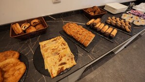 Un bufé con diversas opciones de panadería, incluyendo pasteles, pan y postres.