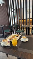 A breakfast setting with a tray of pastries, a glass of orange juice, and two cups of coffee on a table.