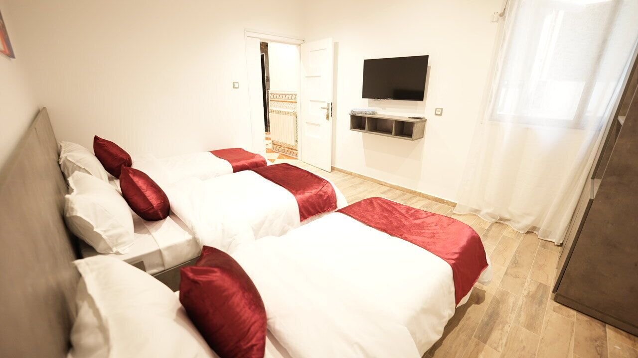 A hotel room with a bed, a television mounted on the wall, and a door leading to a hallway.