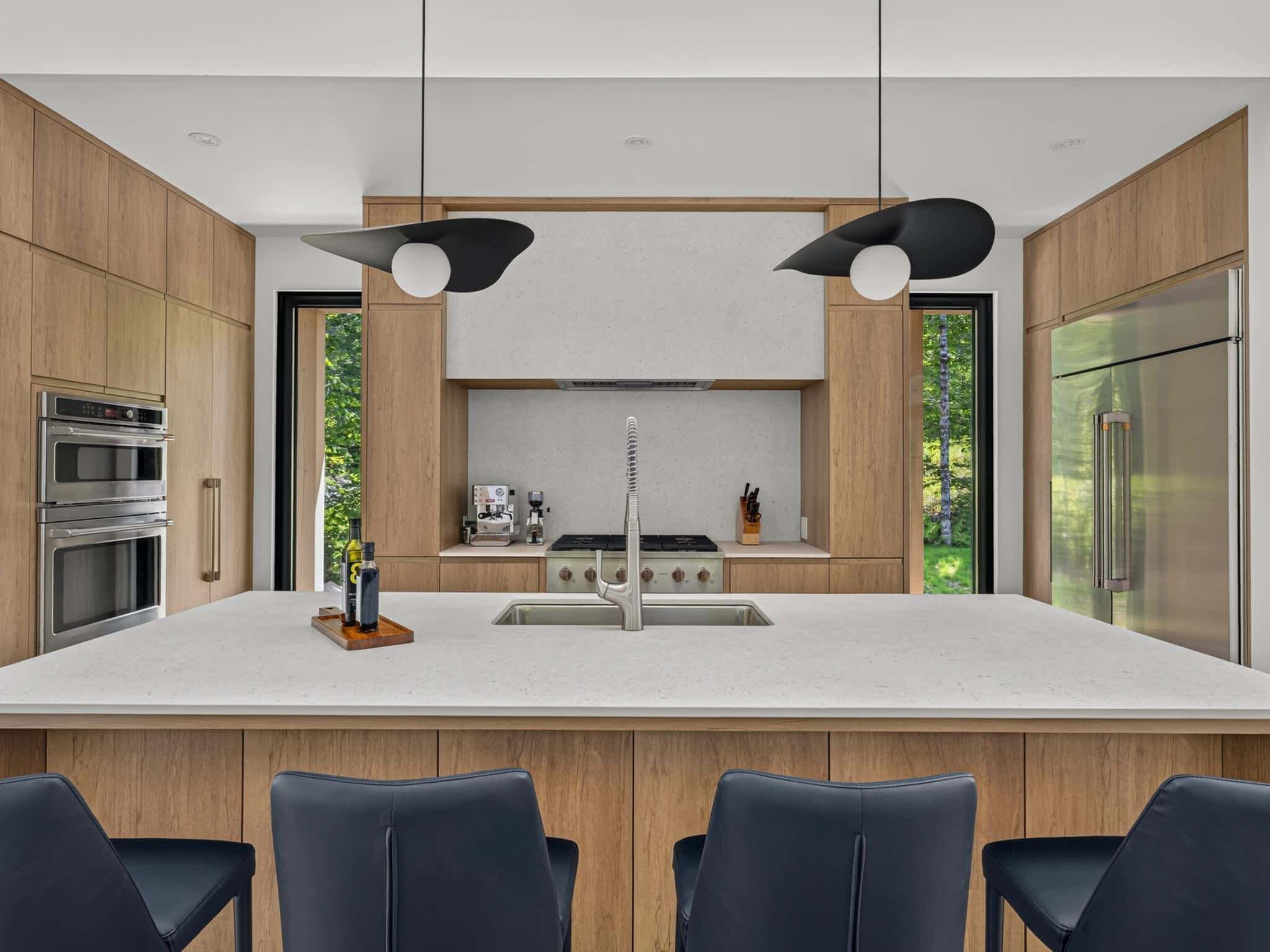 A modern kitchen with a central island, stainless steel appliances, and a bar seating area.