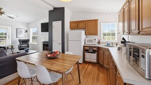 Una cucina moderna con mobili in legno, un tavolo da pranzo con sedie, un forno a microonde e un frigorifero.