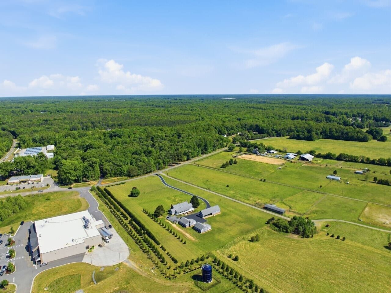 An aerial view of a large property with multiple buildings, green fields, and a road.