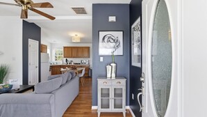Un soggiorno moderno con un divano grigio, una zona pranzo con tavolo in legno e una cucina sullo sfondo.