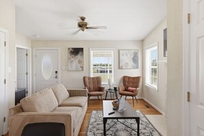 A living room with a beige sofa, two leather armchairs, a coffee table, and a ceiling fan. - Cottage #2 at The Fairway Farm | Disc Golf Getaway (Quinton)